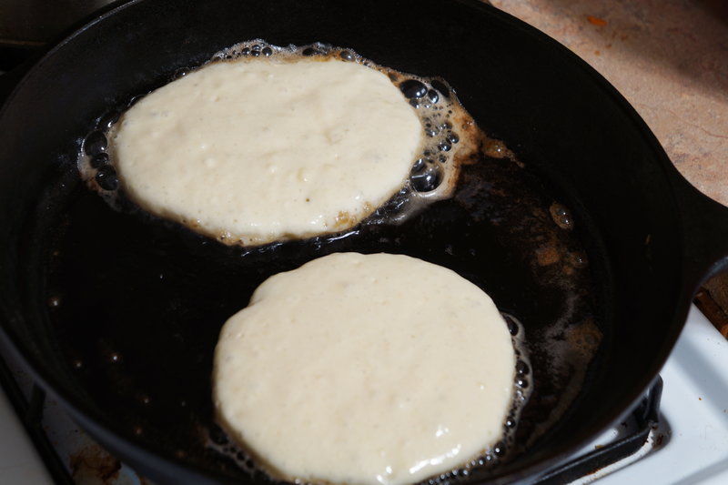 Pancakes cooking over cast iron skillet